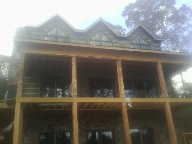 Dormers and porch framing on a large log home under construction — Roof Coating work by our crew in Leesburg